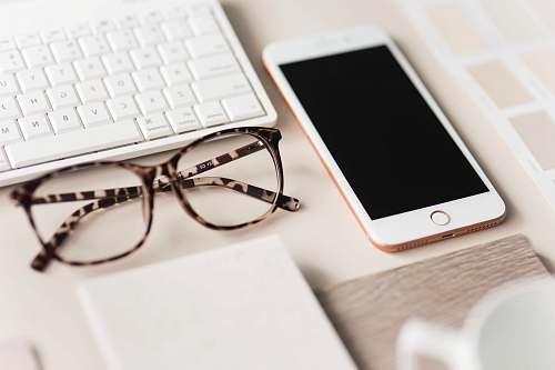 mobile phone gold iPhone 7 beside black and brown framed eyeglasses cell phone